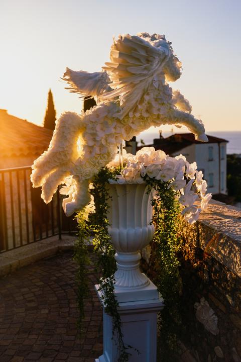 The finished white Pegasus rearing from its urn of orchids at sunrise above the sea